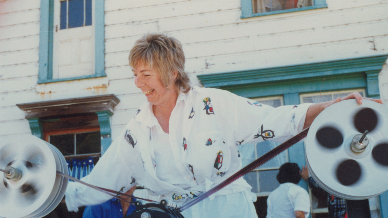 Film subject Vivien smiling while looking at a large spool of film stills